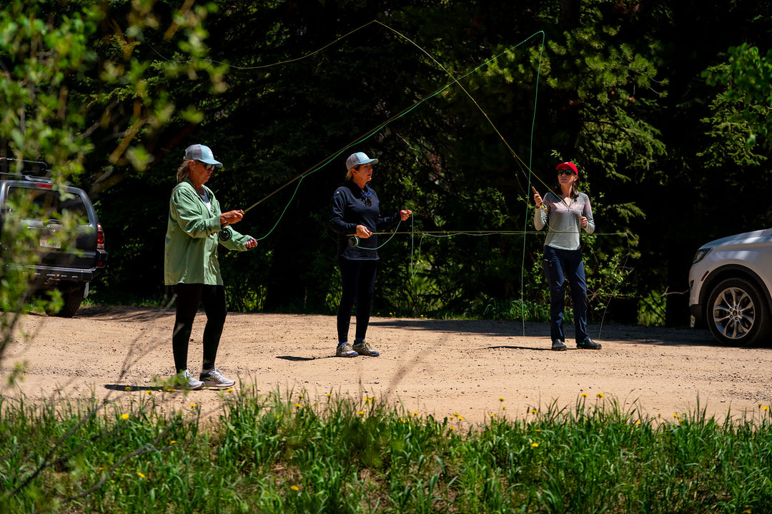 Instructor Holly Jones teaching two women how to cast a fly rod in the Uinta National Forest during a Intro to Fly Fishing Clinic