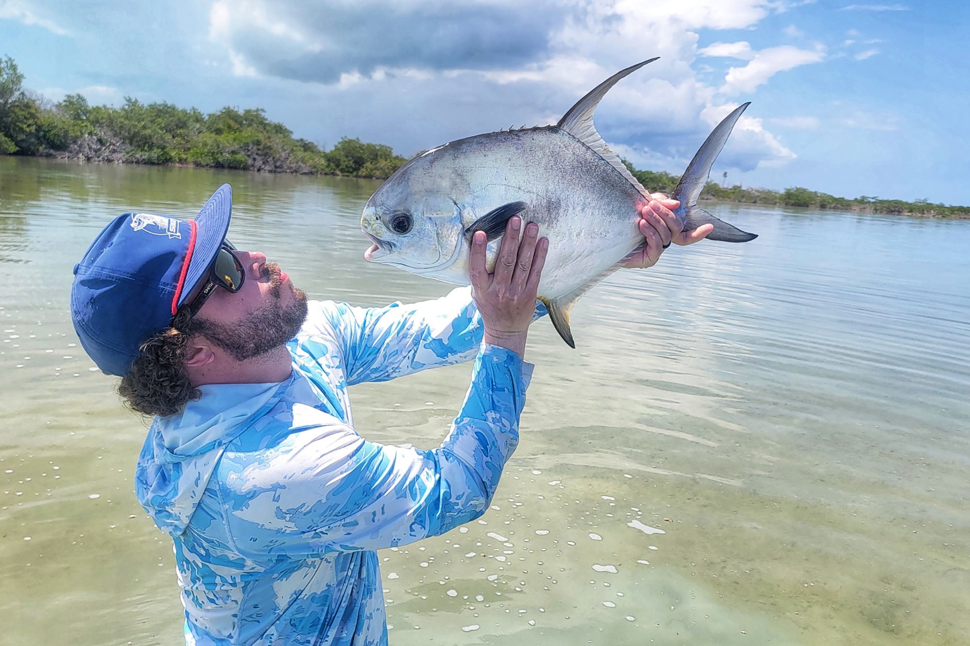 Fishwest travel guest Richard staring straight into the large eyes of Permit caught on the flats near Xcalak, Mexico.